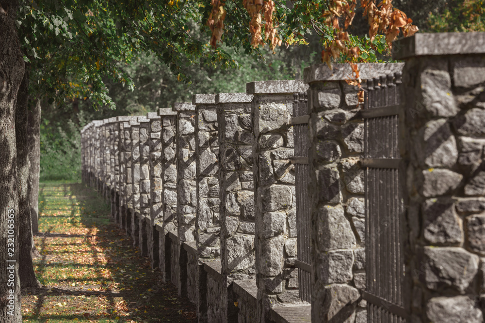 selective focus of stone fence under trees outdoors selective focus of stone fence under trees outdoors