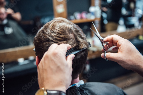 the master in the barbershop shaves and cuts the man