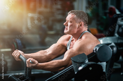 athletic man trains in the gym. Training of biceps on the bench