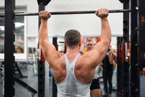 muscular man trains his shoulders with a barbell in the gym. Health and fitness concept