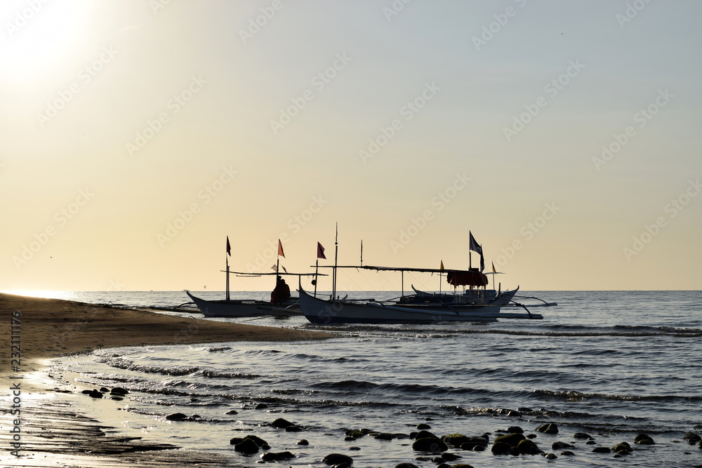 Sun rises over Tourist Boats anchored on Sea shore. Silhouettes
