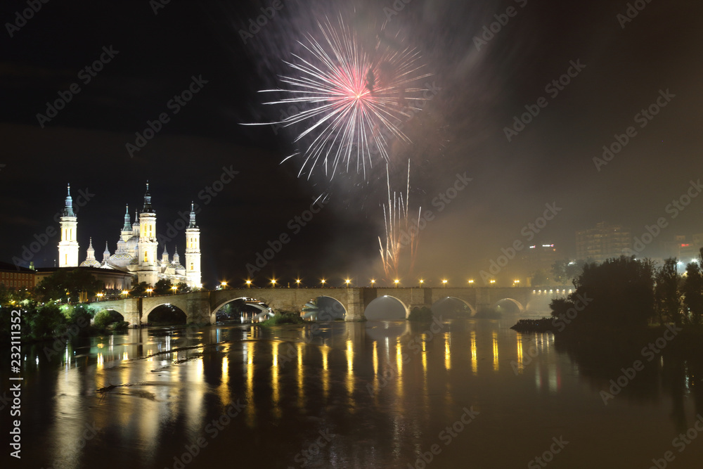 Fototapeta premium The fireworks during the 2018 Pilar festival next to the Pilar Cathedral and the Stone Bridge over the Ebro river, in Zaragoza, Aragon region, Spain