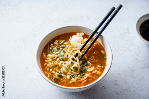 Easy japanese ramen with noodles, pork broth, egg and leek in white bowl on concrete background