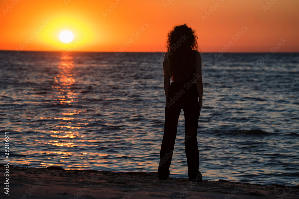 Silhouette young woman on the beach at sunset
