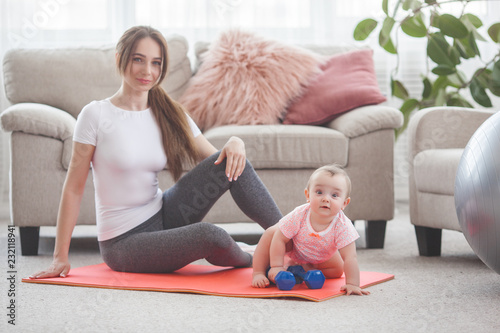 Young pretty mother working out with her little child at home