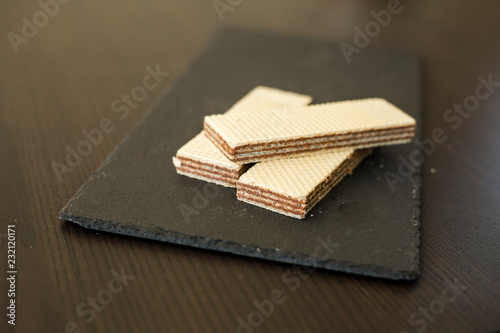 Wafers with chocolate on black slate board, close-up