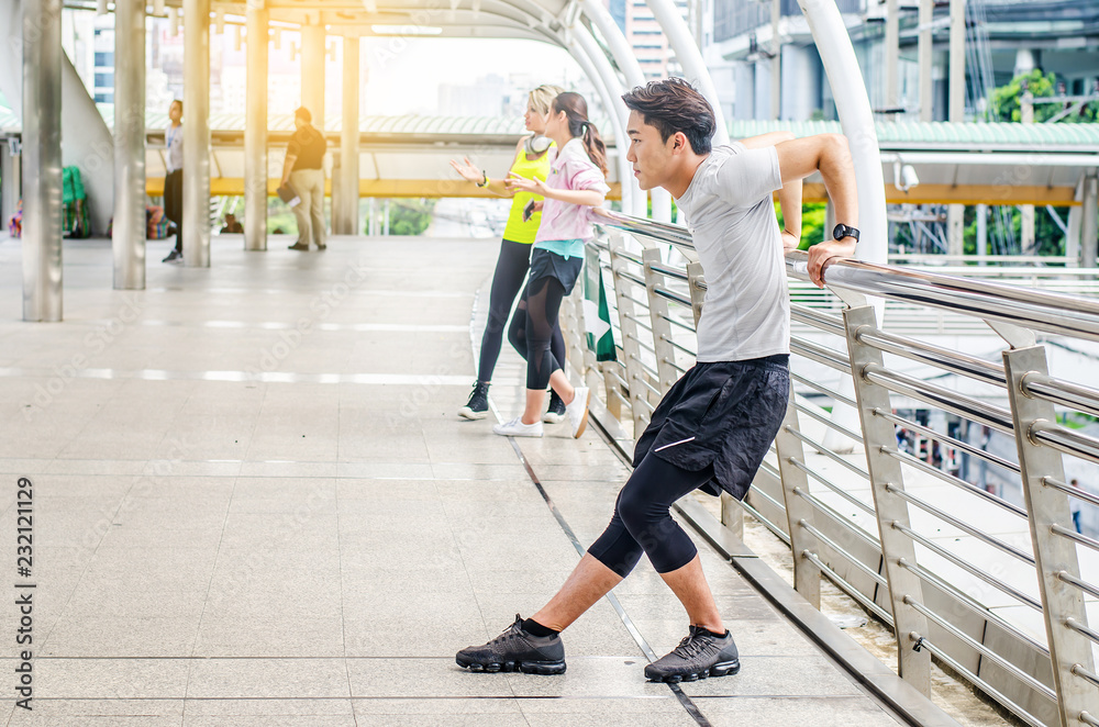 Obraz premium Portrait of a man wearing a sport In the big city doing warm-up exercises before jogging in park, And in another part. 