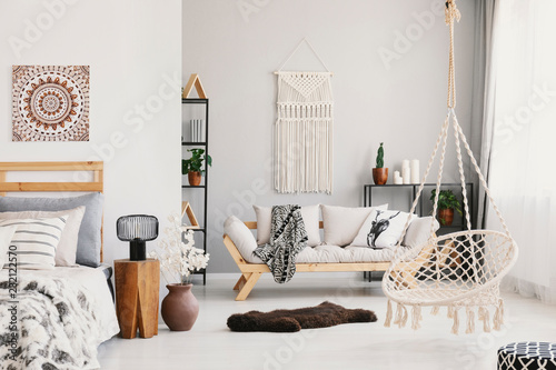 Foto Bright living room interior with macrame on the wall, beige couch with pillow an