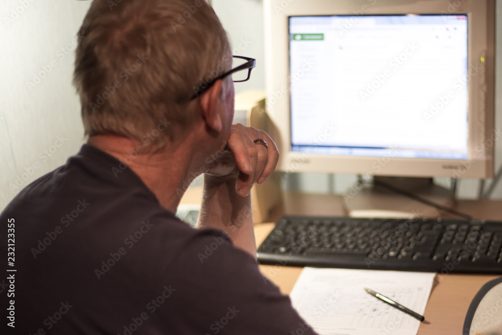 an elderly man working at the computer at home an elderly man working at the computer at home
