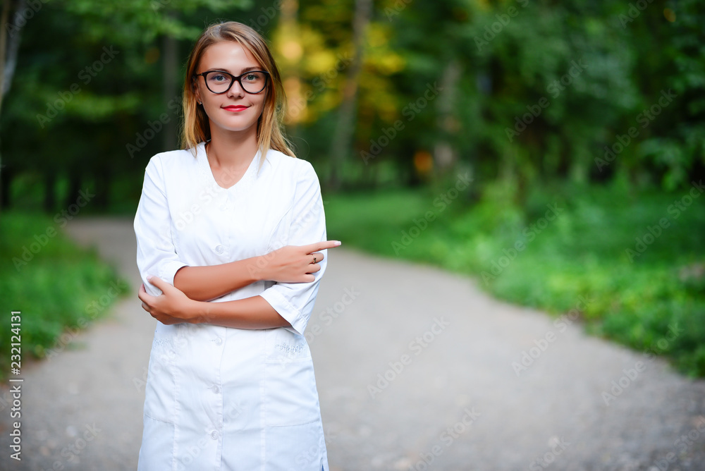Right. a young girl who is a doctor stands outside, shows the index finger of the right hand, to the left