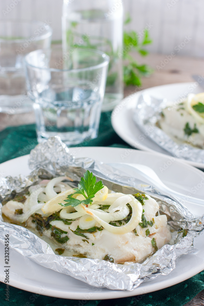 Cod baked in herbs and onions in foil, selective focus Cod baked in herbs and onions in foil, selective focus