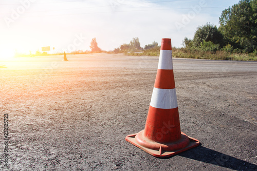 traffic cone, with white and orange stripes on gray asphalt, copy space