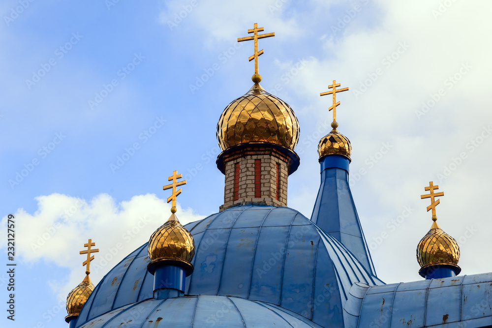 Old Christian church in Kemerovo with golden and gilded domes and blue iron roof against a sky. Concept faith in god, orthodoxy, prayer
