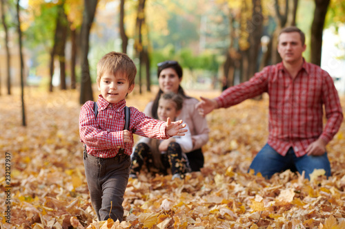 Happy family is in autumn city park. Children and parents. They posing, smiling, playing and having fun. Bright yellow trees.