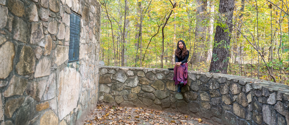 Woman in sarong sitting on stone wall in amphitheater
