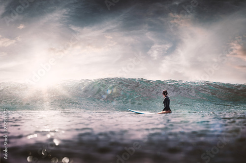 girl with surf board wait big ocean wave,dramatic sky and toning. lifestyle, people water sport lessons and beach swimming activity on summer vacation