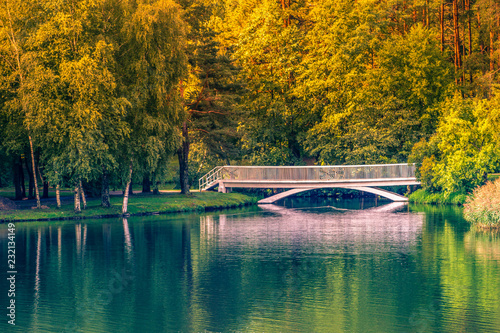 Old small white bridge over lake at sunny autumn day photo