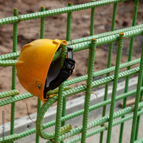 A yellow hard hat hanging on reinforcing bar for a foundation
