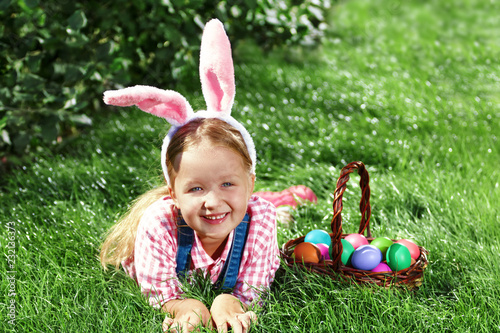 A cheerful little girl preschooler dressed in bunny ears is lyin