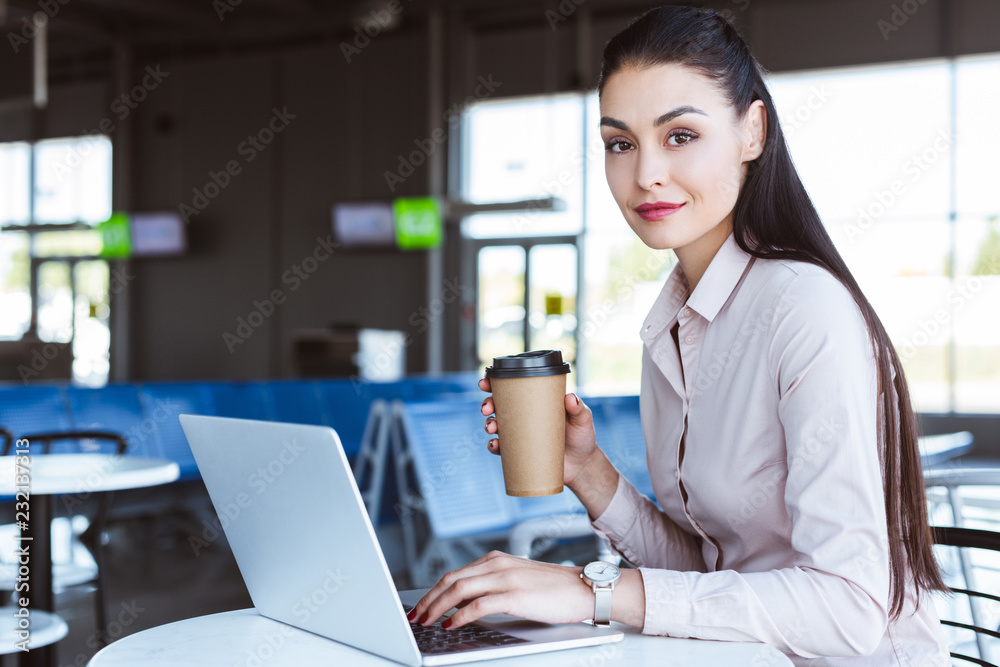 young businesswoman drinking coffee and using laptop at airport young businesswoman drinking coffee and using laptop at airport