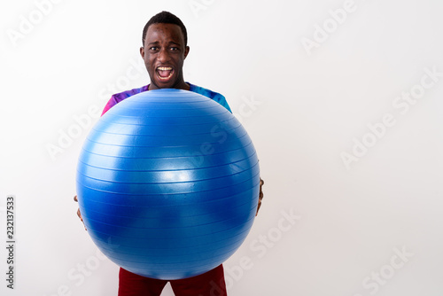Studio shot of young black African man holding big exercise ball