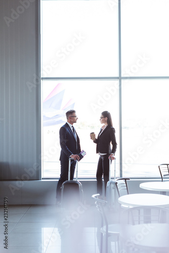businessman and businesswoman standing and talking at departure lounge in airport