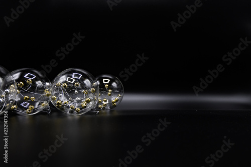 Transparent Christmas balls with golden spheres inside on black.