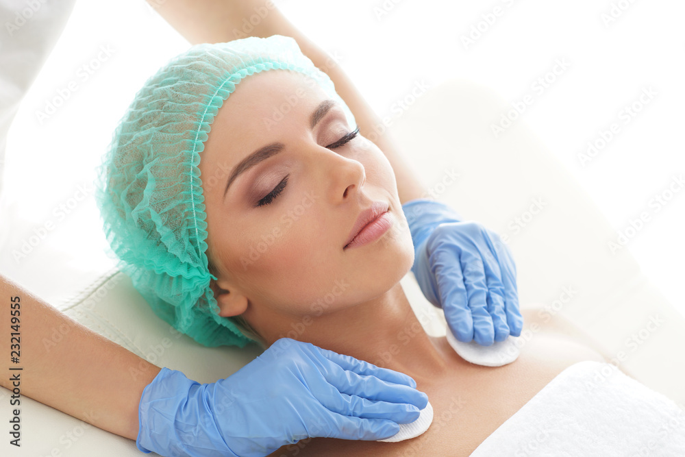 Cosmetologist cleaning face of a young woman with a cotton pads. Removing cosmetics with hygienic discs. Cosmetologist cleaning face of a young woman with a cotton pads. Removing cosmetics with hygienic discs.