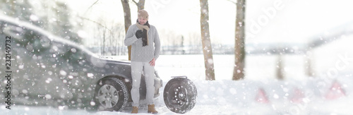 A man near a broken car on a winter day