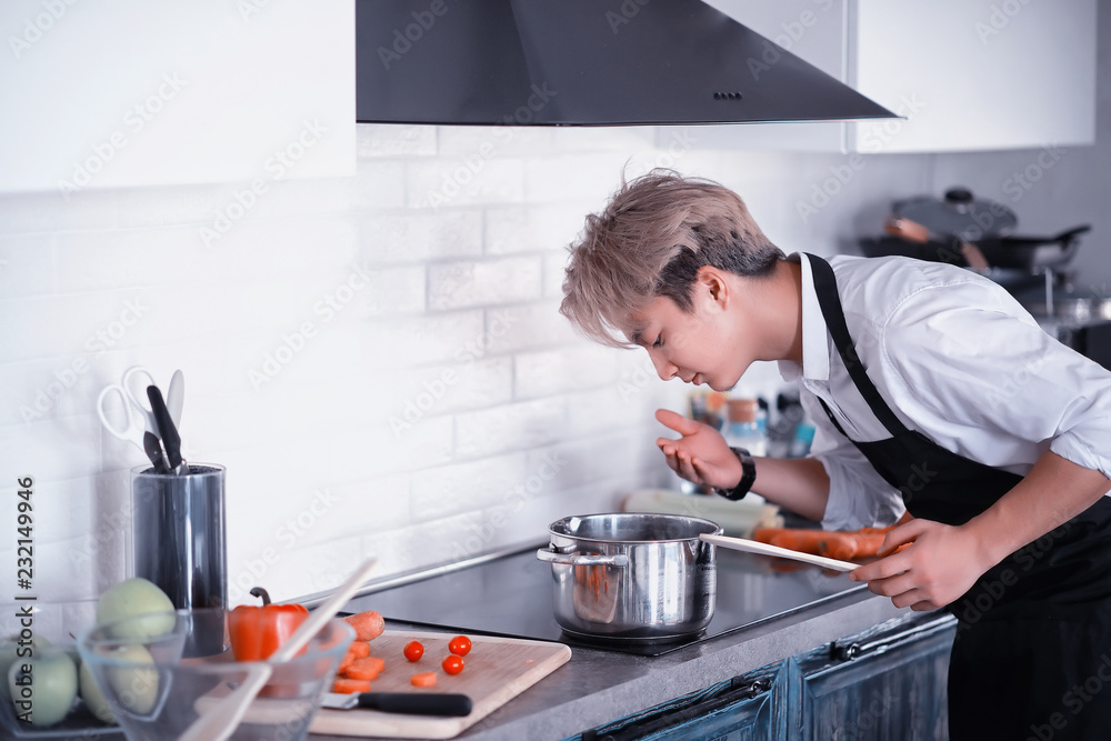Asian cook in the kitchen prepares food in a cook suit