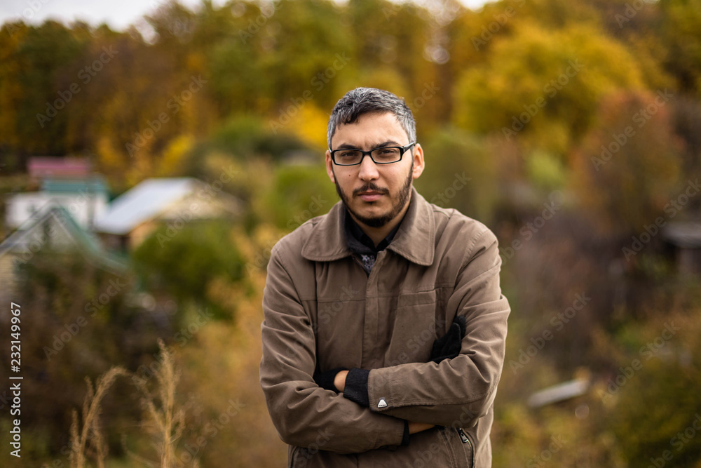 Young man with beard and mustache wearing glasses in brown jacket Young man with beard and mustache wearing glasses in brown jacket