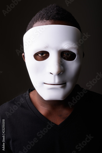 Portrait of young black African man in dark room wearing mask