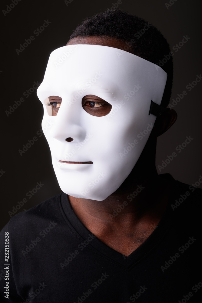 Portrait of young black African man in dark room wearing mask Portrait of young black African man in dark room wearing mask