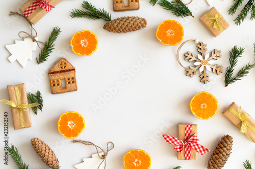 Round frame of Christmas tree branches and decorations with oranges, cookies, gifts, space for text. Top view.