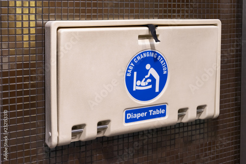 Fototapeta Naklejka Na Ścianę i Meble -  white plastic diaper table on brown ceramic wall in toilet. Baby diaper table in a public restroom