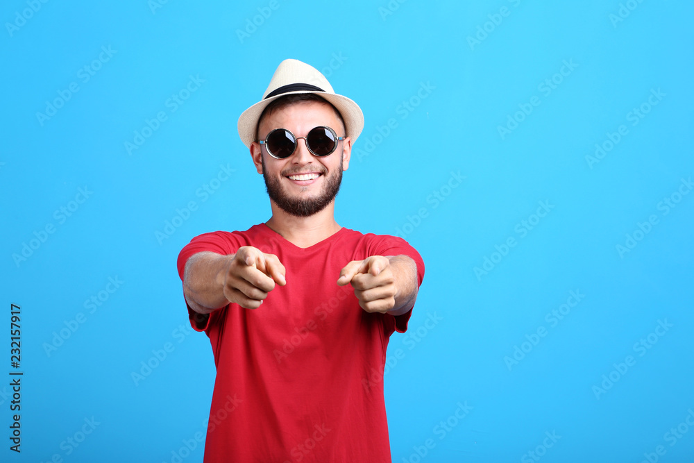 Naklejka premium Young man with sunglasses and hat on blue background