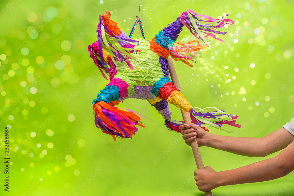 piñata para cumpleaños y navidad, colorida con luces brillantes, fondo verde  y azul con manos de