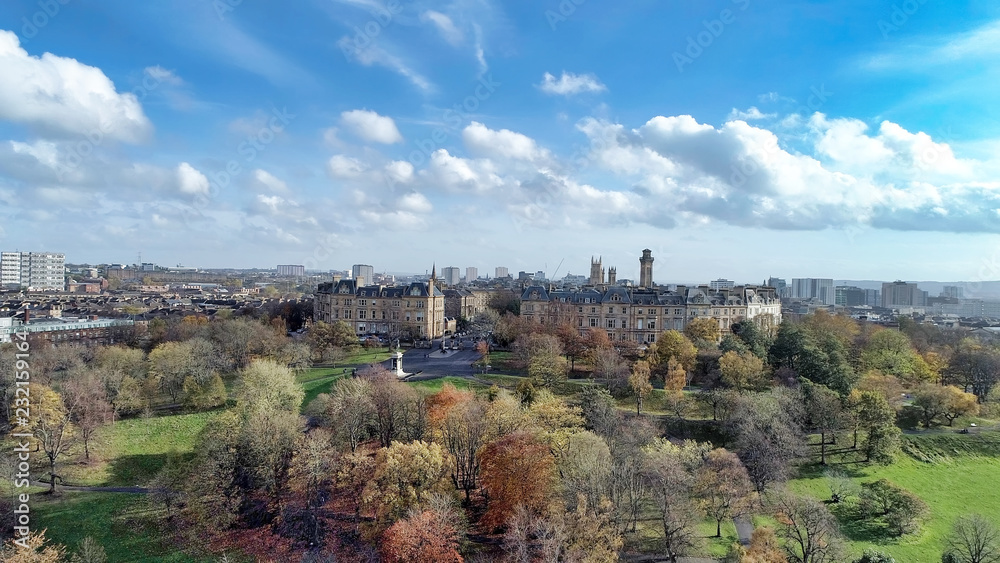 Low level aerial image over the autumn foliage of trees in Kelvingrove Park, Glasgow, to the elegant buildings of Park Circus.