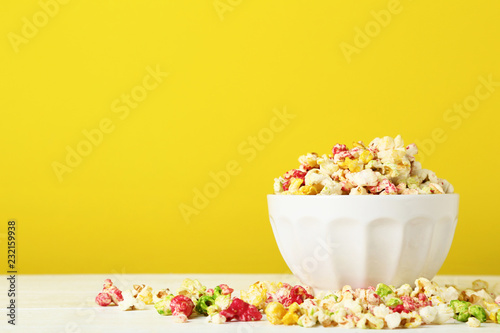 Colorful popcorn in bowl on yellow background
