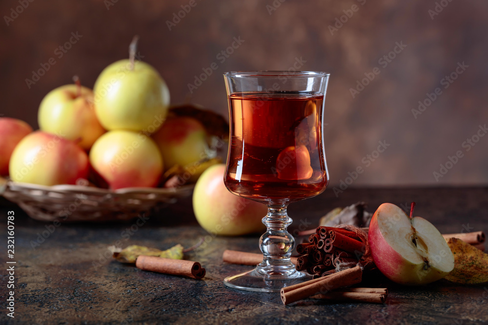 Glass of apple juice or cider with juicy apples and cinnamon sticks. Glass of apple juice or cider with juicy apples and cinnamon sticks.