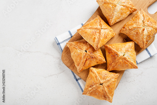Tableau sur toile Puff pastry squares filled with potato, cheese and spinach on light gray stone table