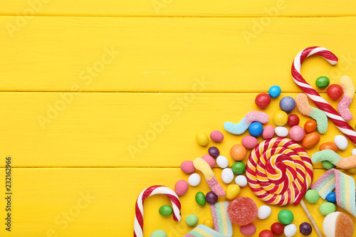 Sweet candies and lollipops on yellow wooden table