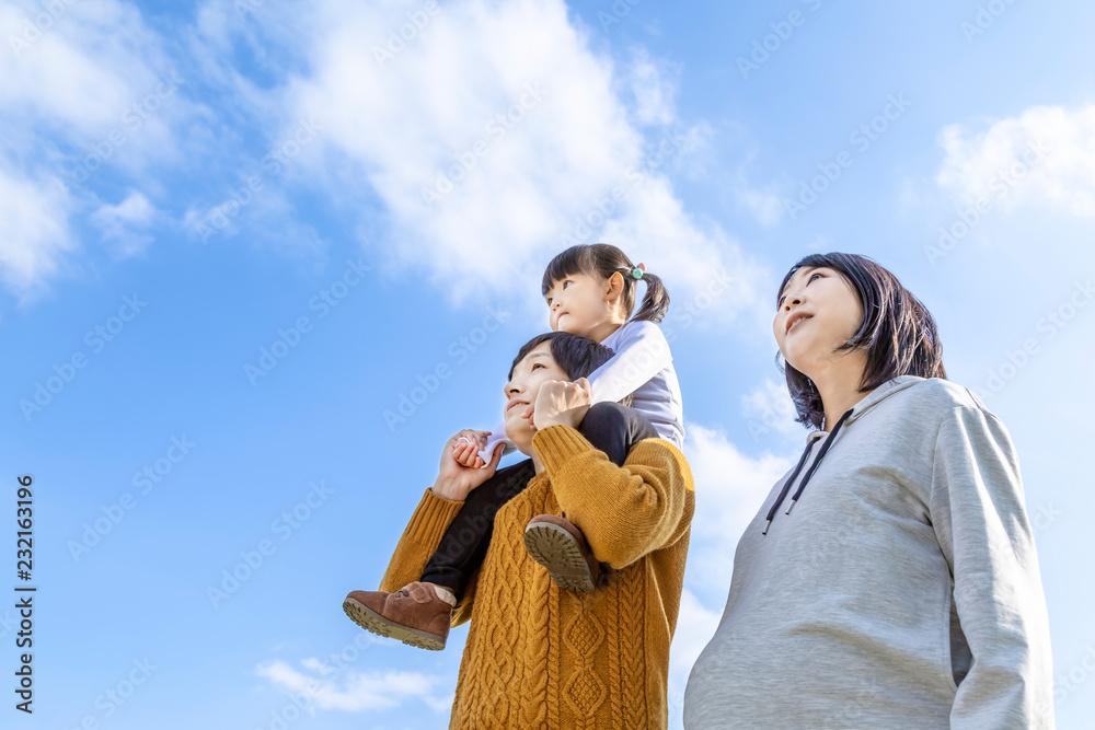 青空を背景に幼い娘を肩車する父と妊娠している母 家族 夫婦 幸せ 愛情イメージ Stock Photo Adobe Stock