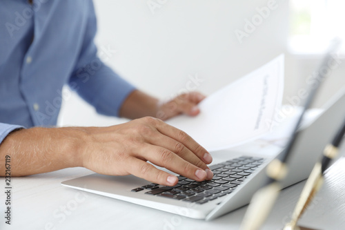 Male notary working with laptop at table in office, closeup © New Africa