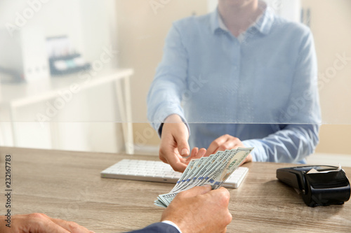 Man giving money to teller at cash department window, closeup photo