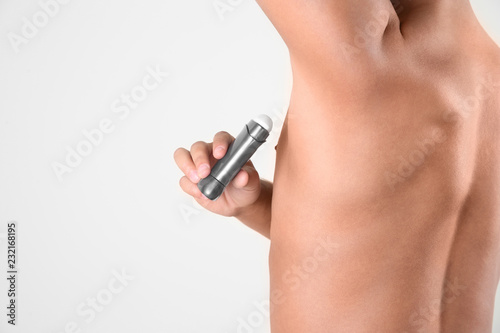 Young man using deodorant on white background, closeup. Space for text