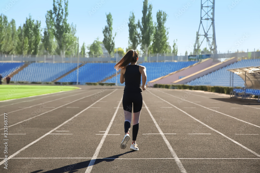 Sporty woman running at stadium on sunny morning
