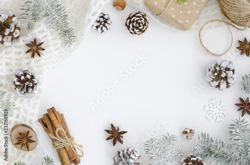 Christmas frame made of hand made Christmas Decoration, cones, cinnamon sticks, anise stars, rope. gift box. Trendy mockup with copy space. White minimal covered with snow