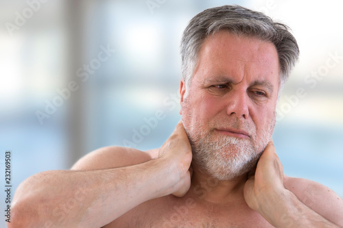 Senior man with a strong pain in the back of his neck front view