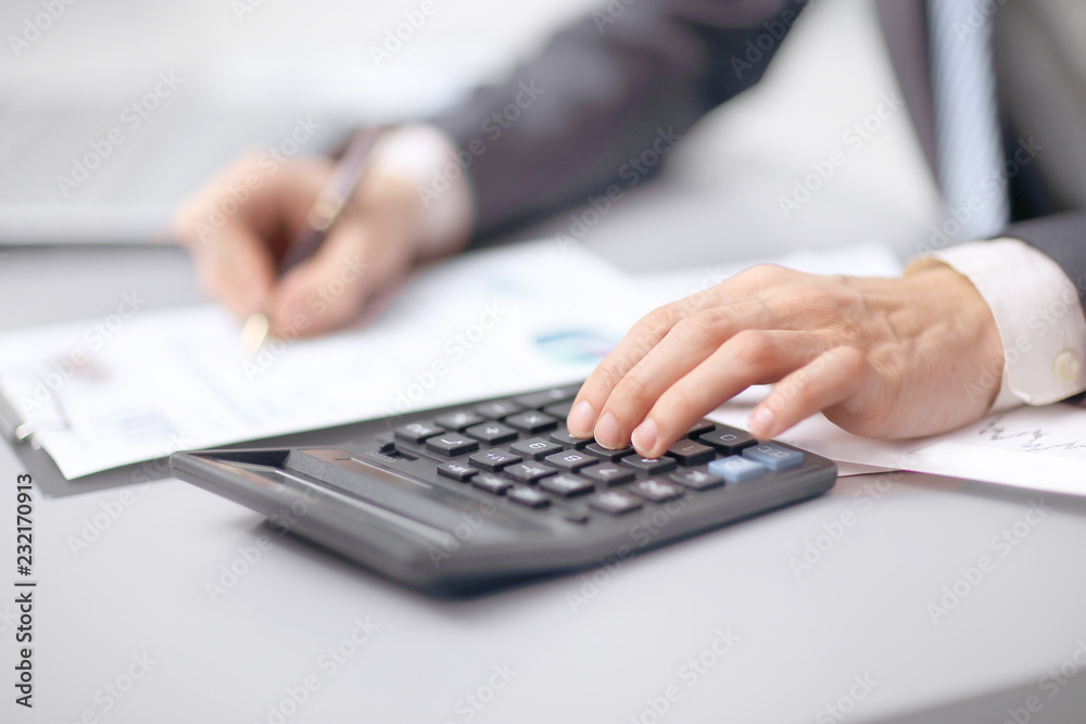 close up. the businessman uses a calculator to check the financial statement close up. the businessman uses a calculator to check the financial statement